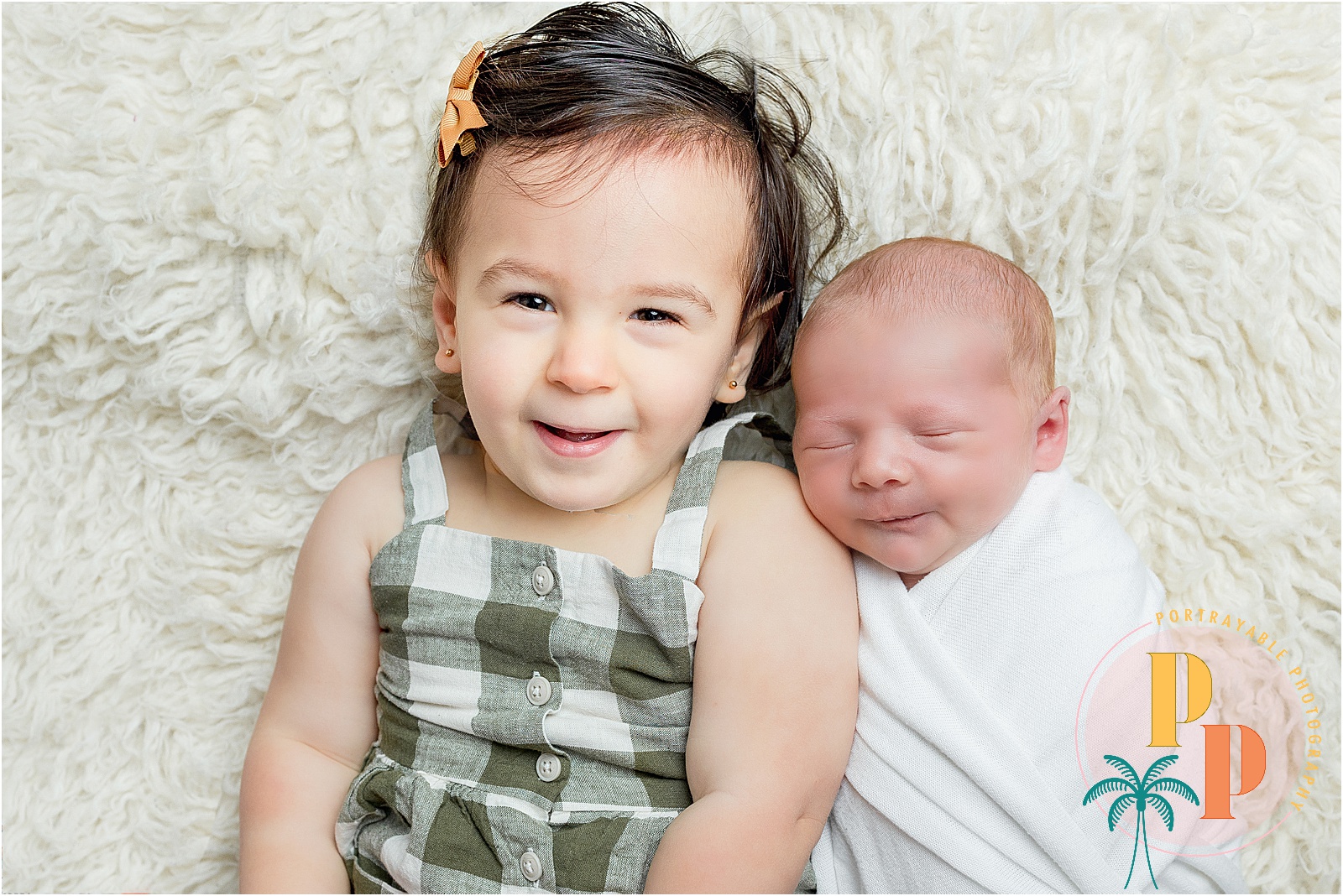 A newborn baby wrapped in a delicate blanket, lying on a soft, neutral-toned surface with big sister in a calm and serene home setting, captured by an Orlando newborn photographer.